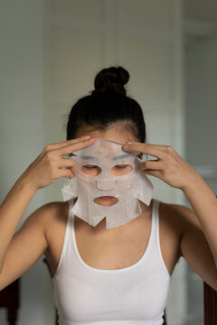 Portraiture of a young asian woman putting on a moisturised face-mask