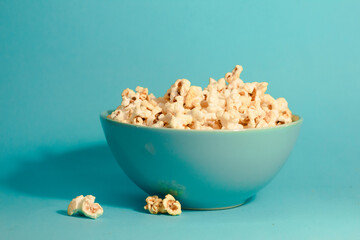 Bright pictures of popcorn. Popcorn in a blue plate. Blue background. Flat lay, copy space. Banner