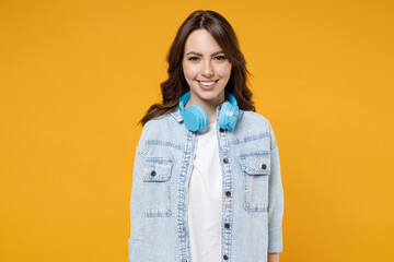 Young caucasian smiling happy brunette student positive friendly woman 20s wear stylish casual denim shirt white t-shirt wearing blue modern headphones isolated on yellow background studio portrait