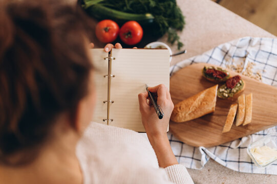 Anonymous woman drawing bruschettas in notebook