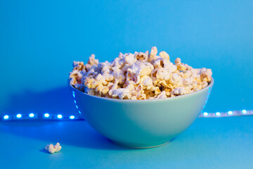 Bright pictures of popcorn. Popcorn in a blue plate. Blue background. Flat lay, copy space. Banner