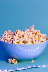 Bright pictures of popcorn. Popcorn in a blue plate. Blue background. Flat lay, copy space. Banner