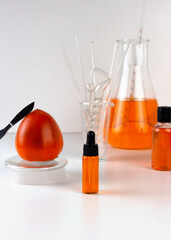 Ripe organic persimmon fruit and persimmon extract in cosmetic bottle with dropper. Abstract chemical or cosmetic laboratory.