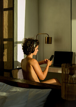 Naked girl works with a smartphone near the workplace