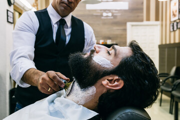 Customer in barbershop being shaved
