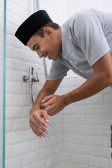 portrait of young Muslim man perform ablution (wudhu) before prayer at home. clean his hand