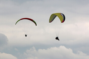 	
Paragliders flying wing in a cloudy sky	