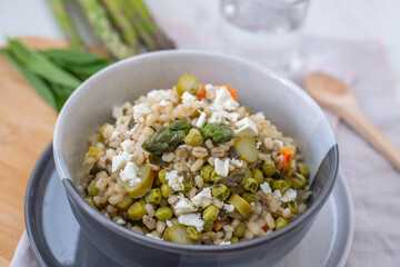 healthy barley soup with spring vegetables, asparagus, wild garlic and carrots