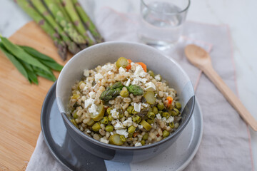 healthy barley soup with spring vegetables, asparagus, wild garlic and carrots