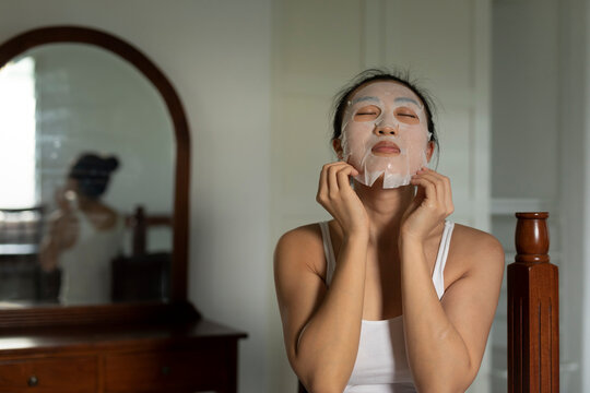Portraiture of a young asian woman putting on a moisturised face-mask