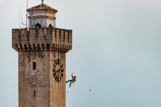 Climber rappelling down tower in city