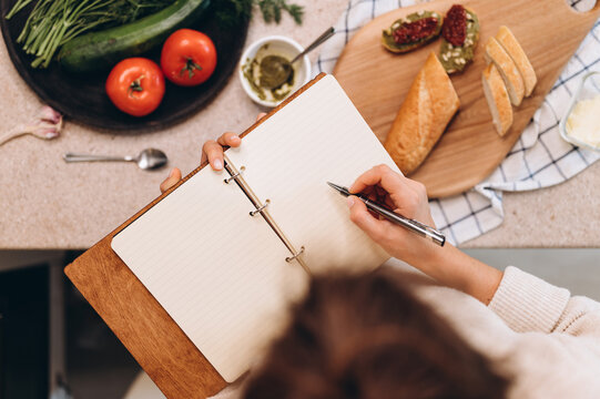 Anonymous woman drawing bruschettas in notebook
