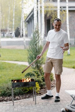 Happy man igniting brazier in yard