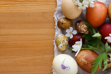 Modern pastel easter eggs with spring flowers on rustic linen cloth on wooden table. Happy Easter!