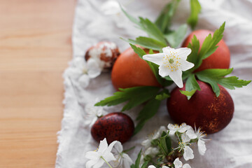 Modern red easter eggs with spring flowers on rustic linen cloth on wooden table. Happy Easter!