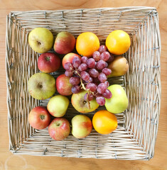 Square woven straw basket holding variety of citrus fruits. 