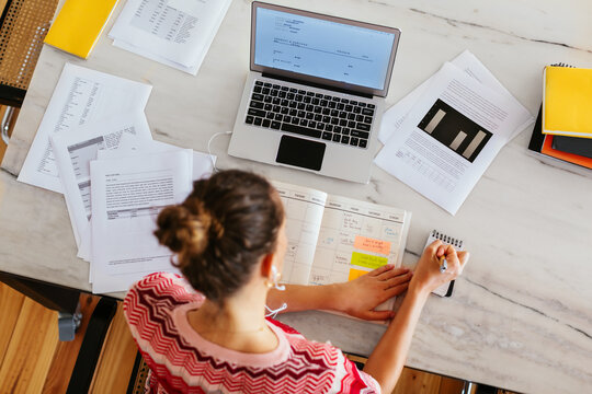 Anonymous woman making notes in home office