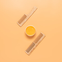 Creative layout made of hair mask and a wooden comb on pastel yellow background. Top view.