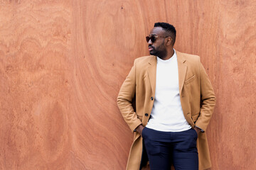 Handsome black man leaning against a wall looking aside.