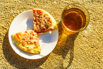 Tea mug and pizza slices on plate, outdoors