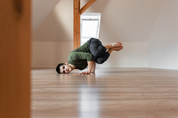 Strong guy doing break dance in attic