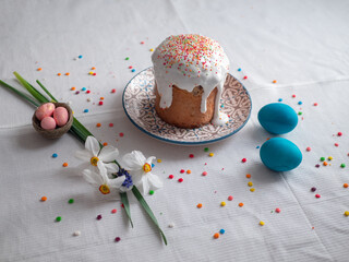Stylish easter eggs natural dyed and homemade easter cake on rustic cloth with flowers on wooden table. Happy Easter. Traditional Easter food.
