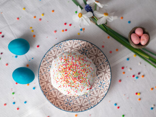 Stylish easter eggs natural dyed and homemade easter cake on rustic cloth with flowers on wooden table. Happy Easter. Traditional Easter food.