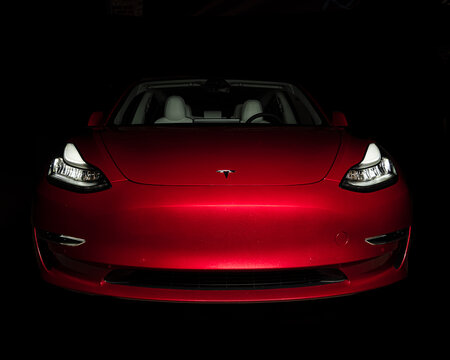 Red Tesla Model 3 photographed in the dark