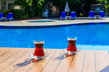 Fototapeta na wymiar Hot turkish tea on a table near a swimming pool