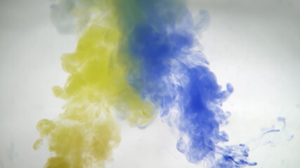 Mixing yellow and blue paint colors in water. Colored smoke effect