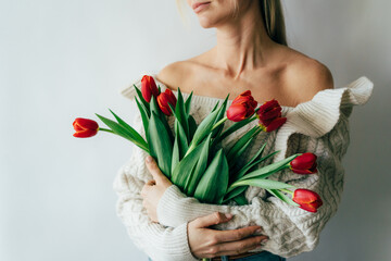A young woman holds a gorgeous bouquet of red tulips in her hands. Festive flower spring concert.