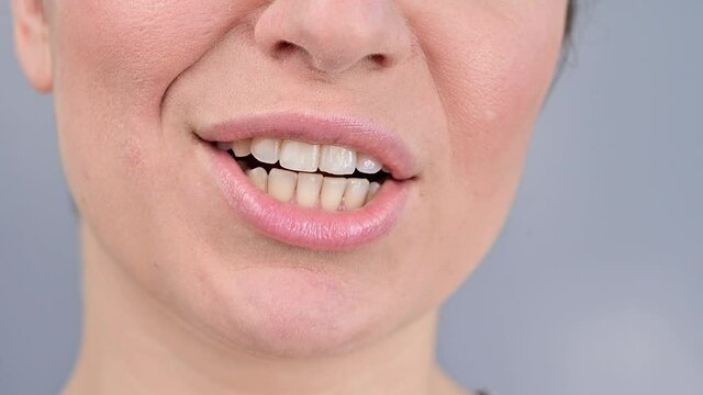 Close-up portrait of a woman smiling and licking her teeth.