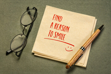 Find a reason to smile - inspirational handwriting on a napkin with a cup of coffee, positive...