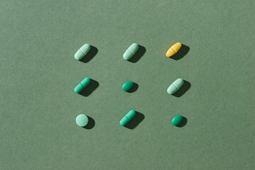 Different colorful pills on green background