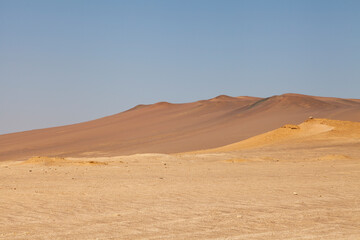 Fototapeta na wymiar Landscape photography of red dunes and yellow sands, in the Paracas desert, on the Lagunillas Route, in the direction of Las Minas Beach in the Paracas National Reserve, Pisco, Ica, Peru.
