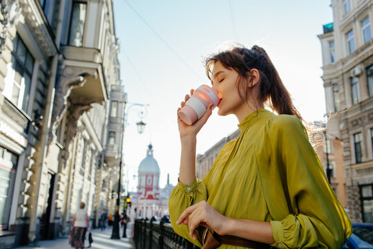 Stylish woman drinking coffee on city street