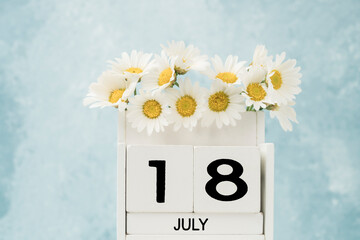 White cube calendar for july decorated with daisy flowers