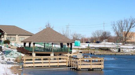 The wood dock and gazebo at the lake on a sunny day.