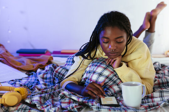 Black teenager using smartphone on bed