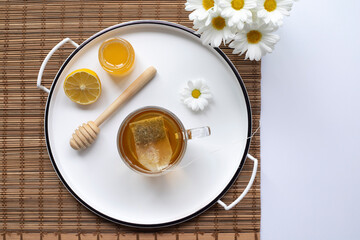 Chamomile tea, honey, lemon and flowers on the decorative tray. Top view. Prevention of seasona flu colds