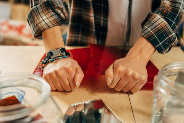 Artist breaks glass with hands while preparing mosaics at her modern studio