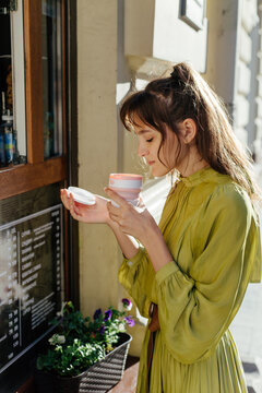 Stylish woman drinking coffee on city street