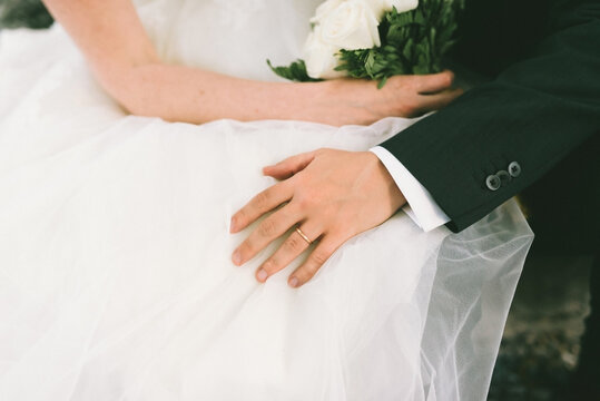 close up of bride and groom sitting down and holding hands close to each other