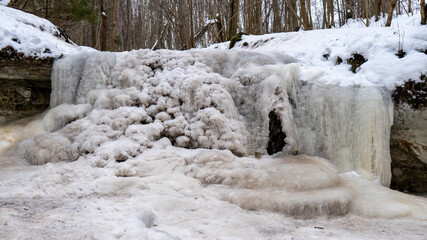 Fototapeta na wymiar Dauda waterfall in winter. Small Frozen waterfall in Gauja national park, Sigulda, Latvia.