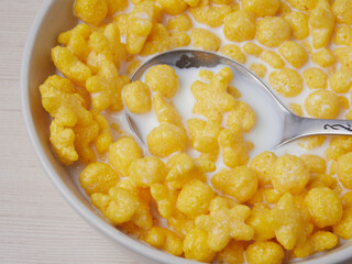 Tasty corn flakes in bowl with bottle of milk. Rustic wooden background with homespun napkin. Healthy crispy breakfast snack. Place for text. Top view, flat lay.