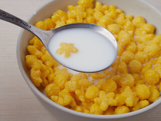 Tasty corn flakes in bowl with bottle of milk. Rustic wooden background with homespun napkin. Healthy crispy breakfast snack. Place for text. Top view, flat lay.
