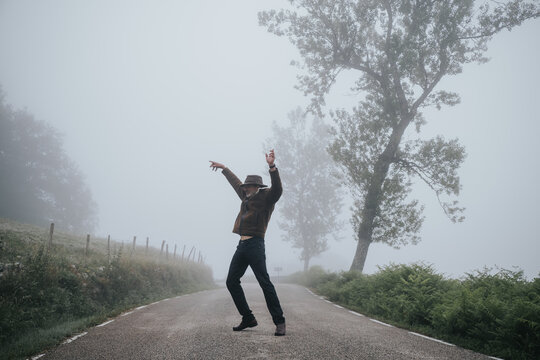 a tall man dances on an empty road in the fog