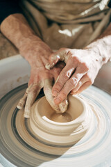 Potter’s hand correcting during shaping clay blank on a potter's wheel