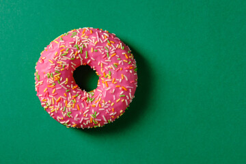 Sweet pink donut on green background