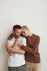Modern Gay Couple Embracing against White